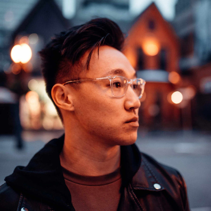 Man wearing glasses with a blurred street scene in the background