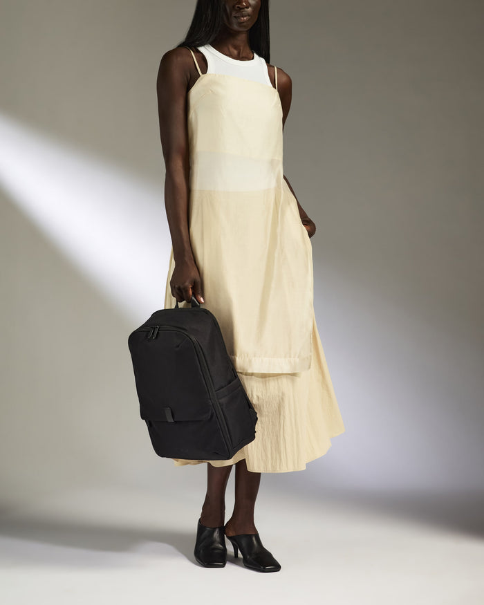 a woman in a white dress holding a black bag