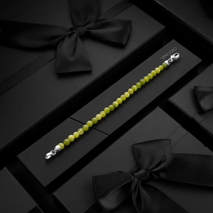 Green beaded bracelet with silver clasp on a black box with black ribbons