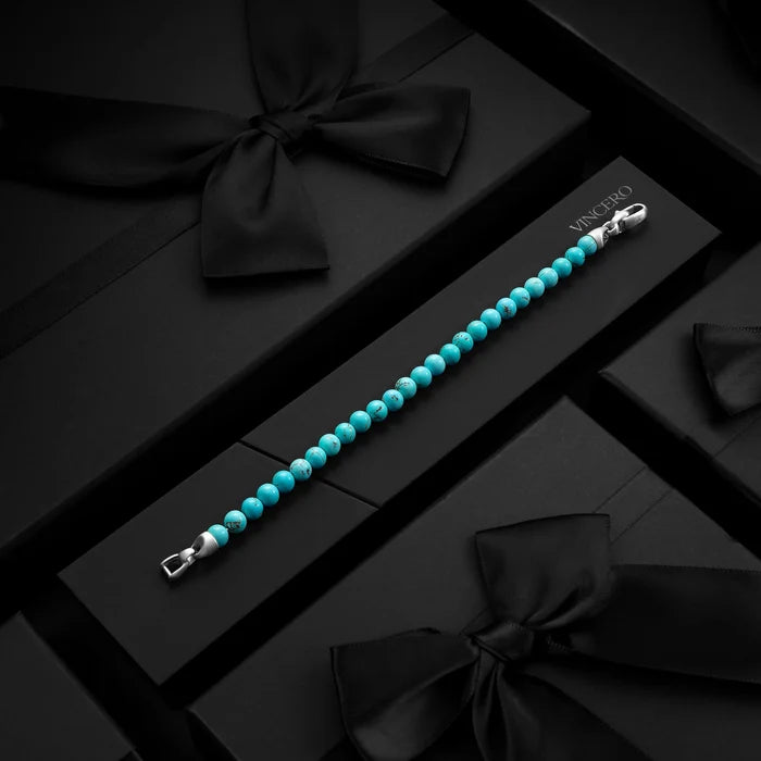 Turquoise beaded bracelet with silver clasp on a black gift box with black ribbons.
