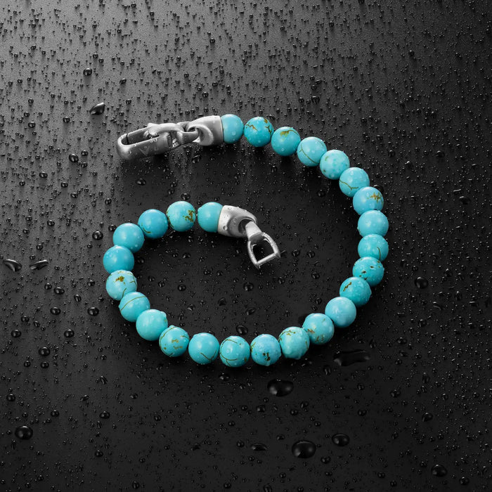 Turquoise beaded bracelet with silver clasp on a dark textured surface