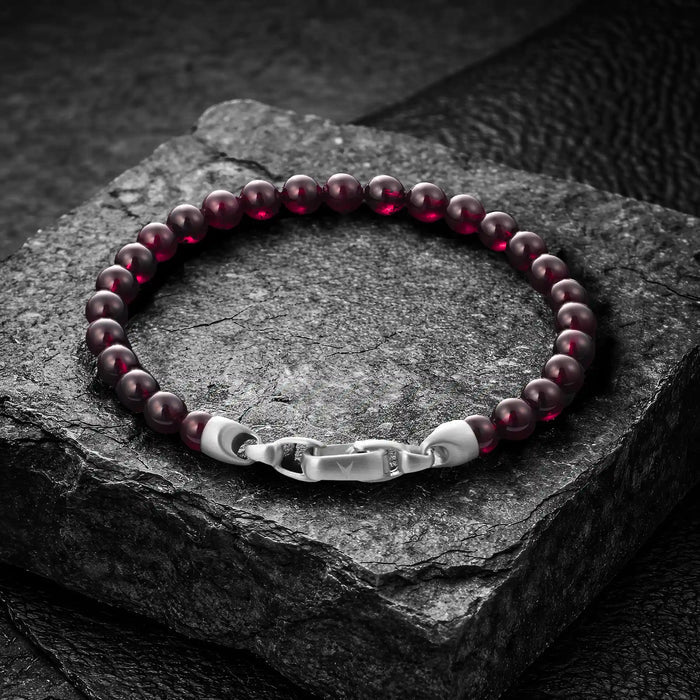 Garnet beaded bracelet with silver clasp on a dark stone surface