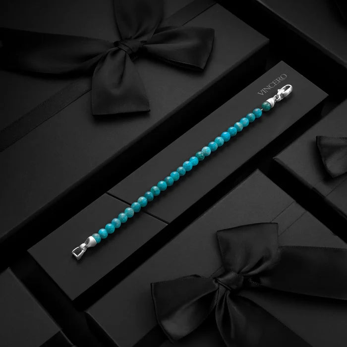 Turquoise beaded bracelet with silver clasp on a black box with black ribbons