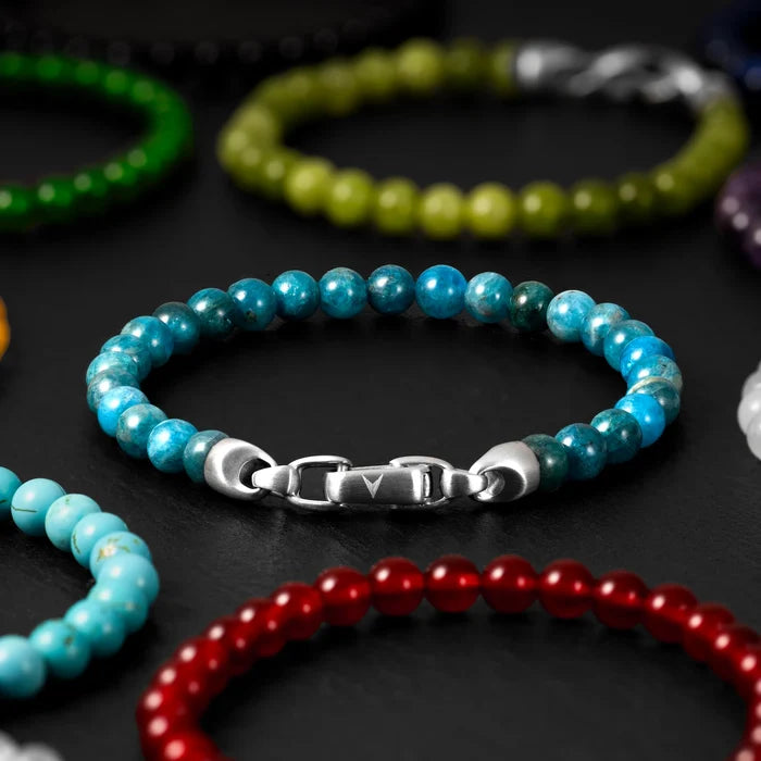 Colorful beaded bracelets with metal clasps on a dark surface