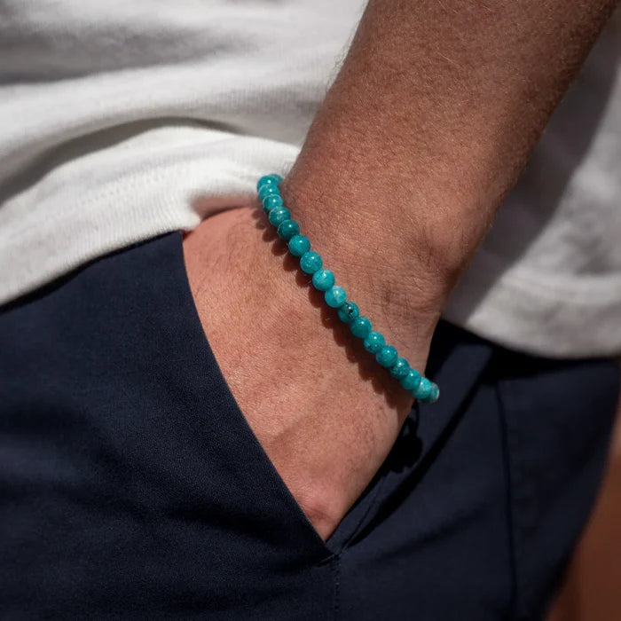 Turquoise beaded bracelet on a wrist with a neutral background