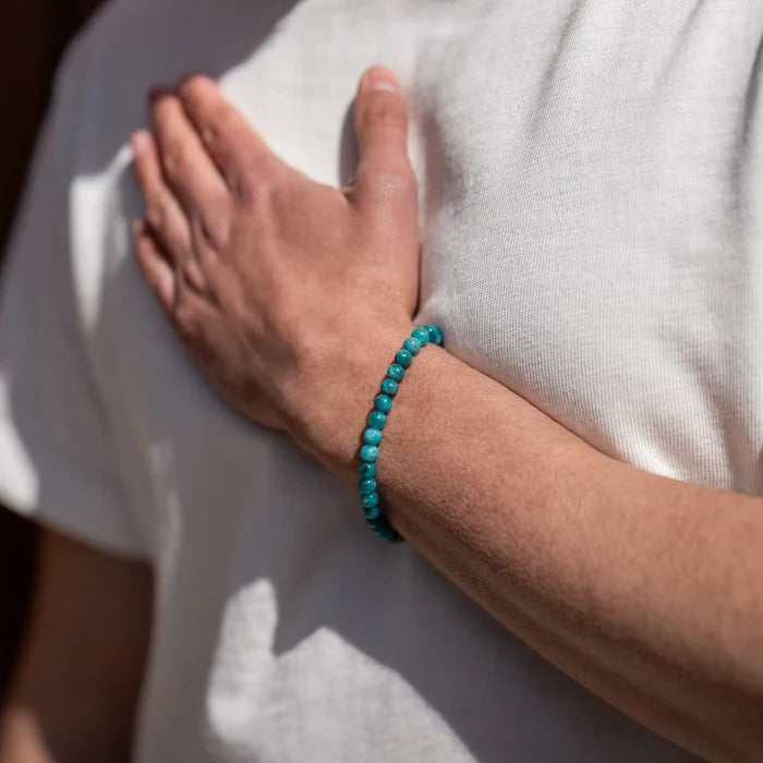 Person wearing a turquoise bracelet on a white shirt