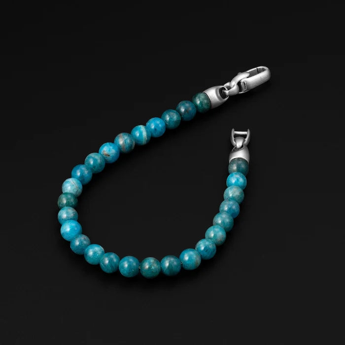 Turquoise beaded bracelet with silver clasp on a black background