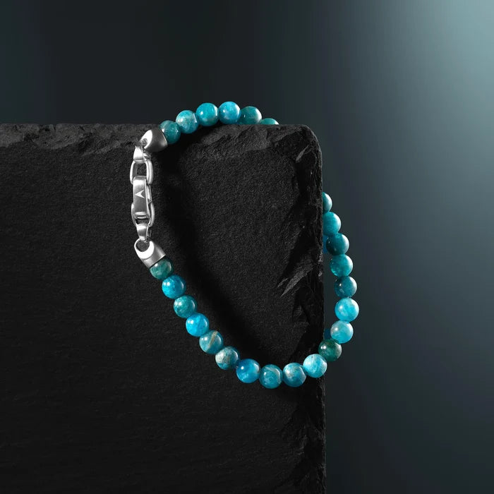 Turquoise beaded bracelet on a black stone surface with a dark background