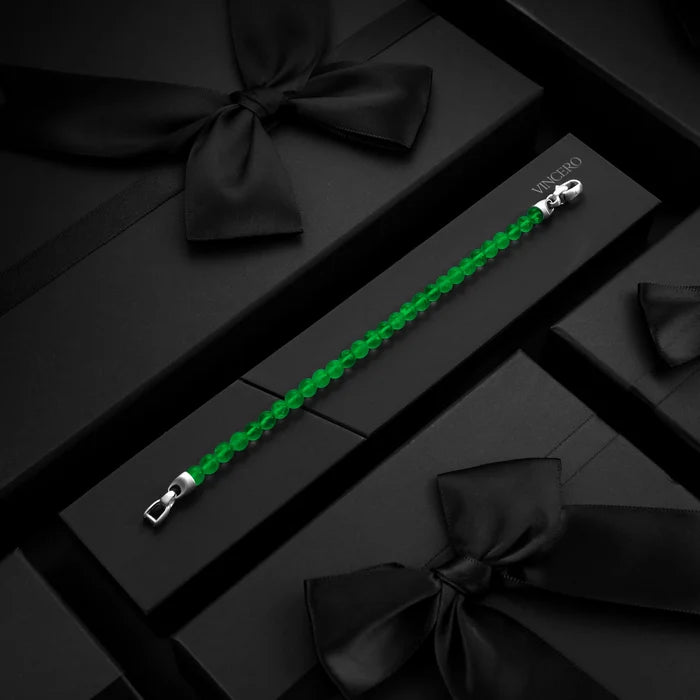 Green beaded bracelet with silver clasp on a black box with black ribbons