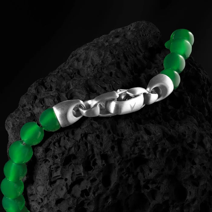 Green beaded bracelet with a silver chain on a dark rock background