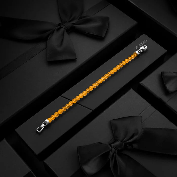 Orange beaded bracelet with silver clasp on a black box with black ribbons