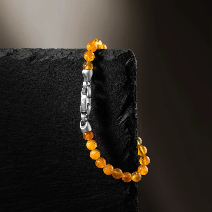 Bracelet with orange beads and a silver clasp on a dark stone surface