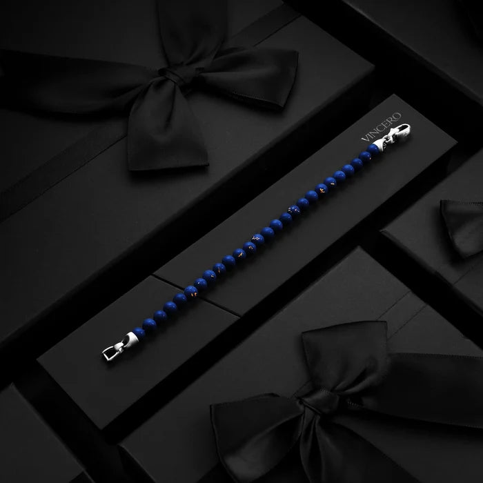 Blue beaded bracelet with silver clasp on a black surface with decorative bows