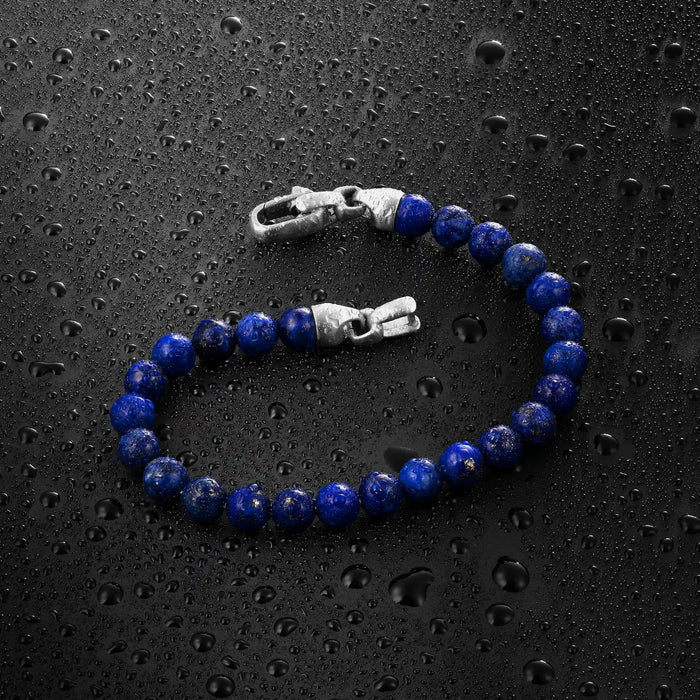 Blue beaded bracelet with silver clasp on a wet black surface
