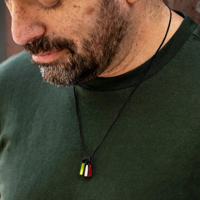 Man wearing a green shirt with a necklace featuring a small pendant.