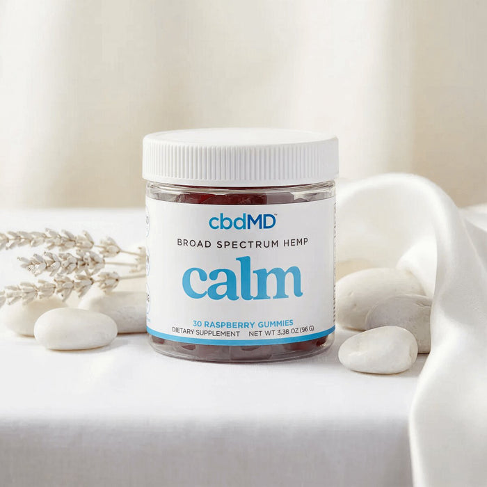 Broad spectrum hemp calming gummies jar with white stones and dried lavender on soft fabric