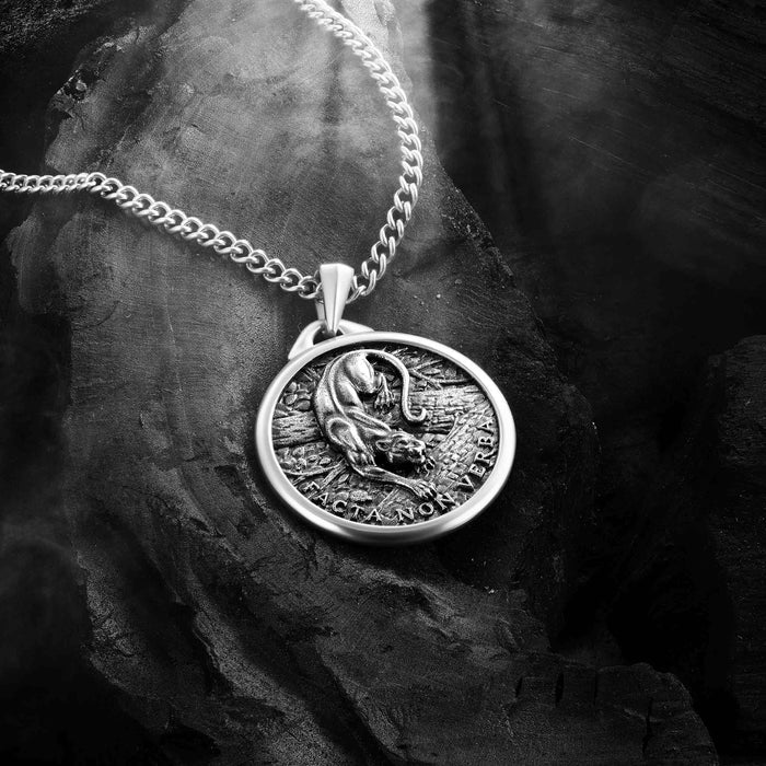 Silver necklace with a round pendant featuring a panther design on a dark stone surface