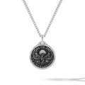 Silver necklace with a round pendant featuring an engraved design on a white background