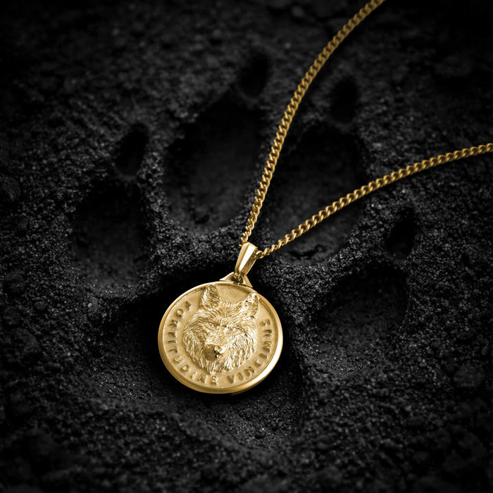 Gold necklace with a wolf pendant on a dark textured background