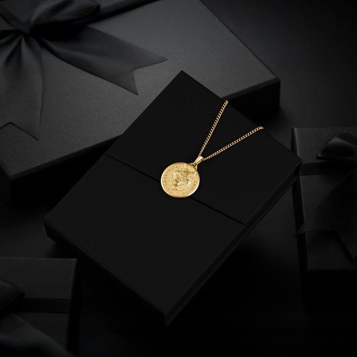 Gold necklace with a pendant on a black box with a black bow in the background