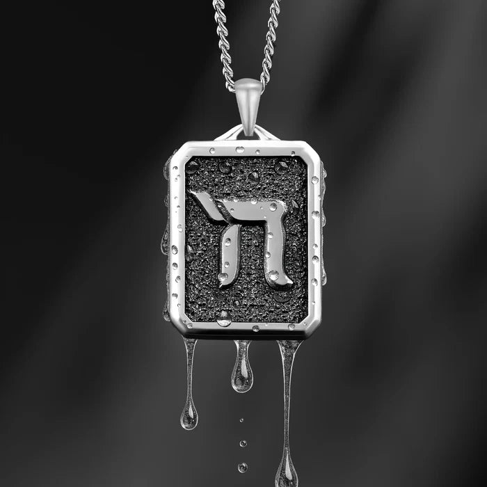 Silver pendant with a black square design on a dark background