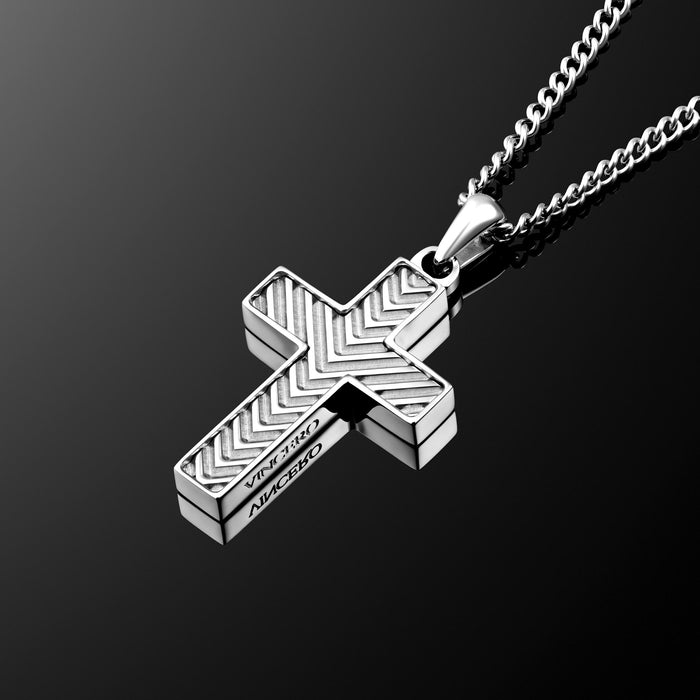 A silver cross pendant necklace with a textured chevron pattern and the engraved words 'JESUS IS LORD' and 'AMEN' on a dark reflective background.