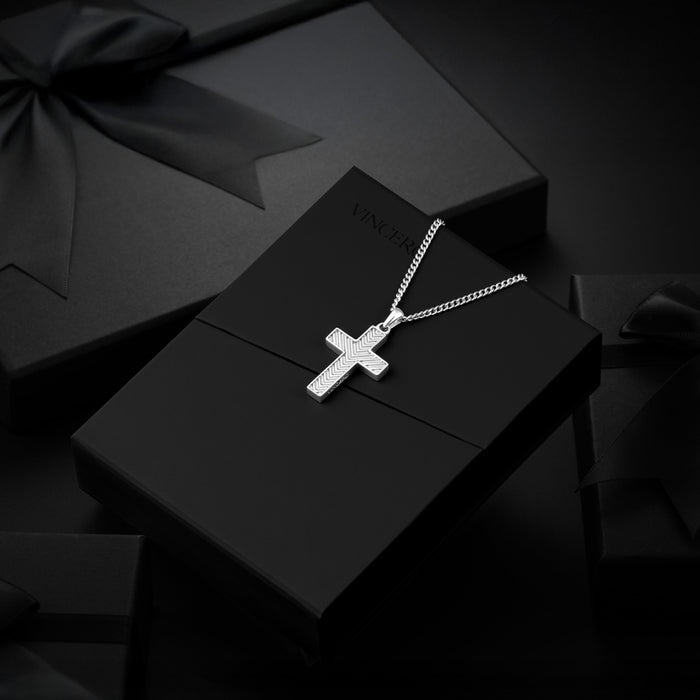 A silver cross pendant necklace with a textured, pave-like setting, displayed on a black gift box. The box has the brand name 'VINCI' partially visible on the lid.