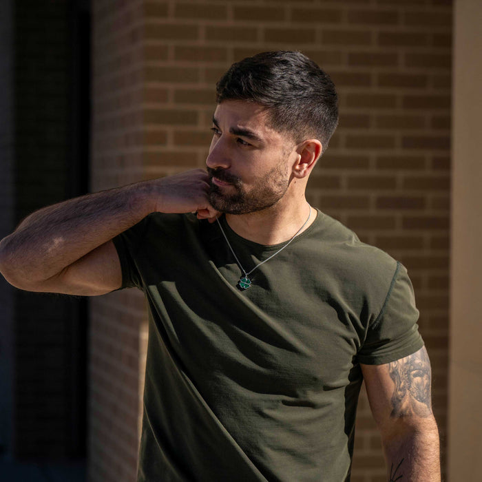 Man wearing a green t-shirt with a brick wall background