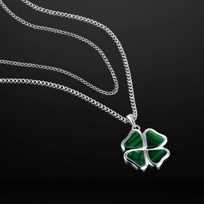 Four-leaf clover pendant on a silver chain against a black background