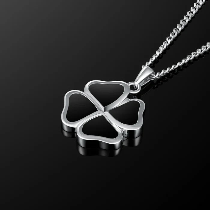 A silver four-leaf clover pendant necklace with a matching chain, displayed on a reflective black surface.