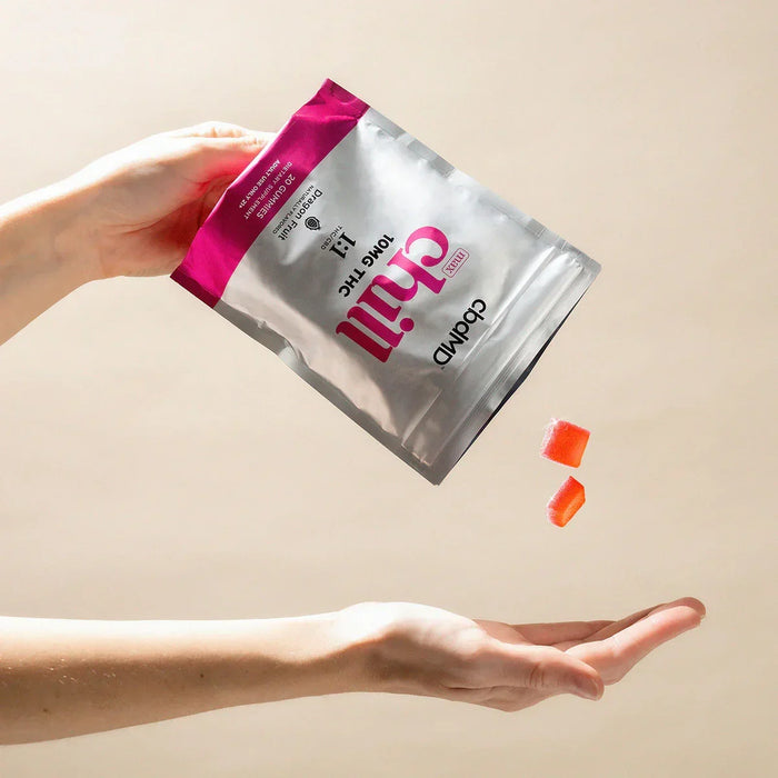 Hand pouring cbd-infused Chill gummies from pouch into open palm on neutral background