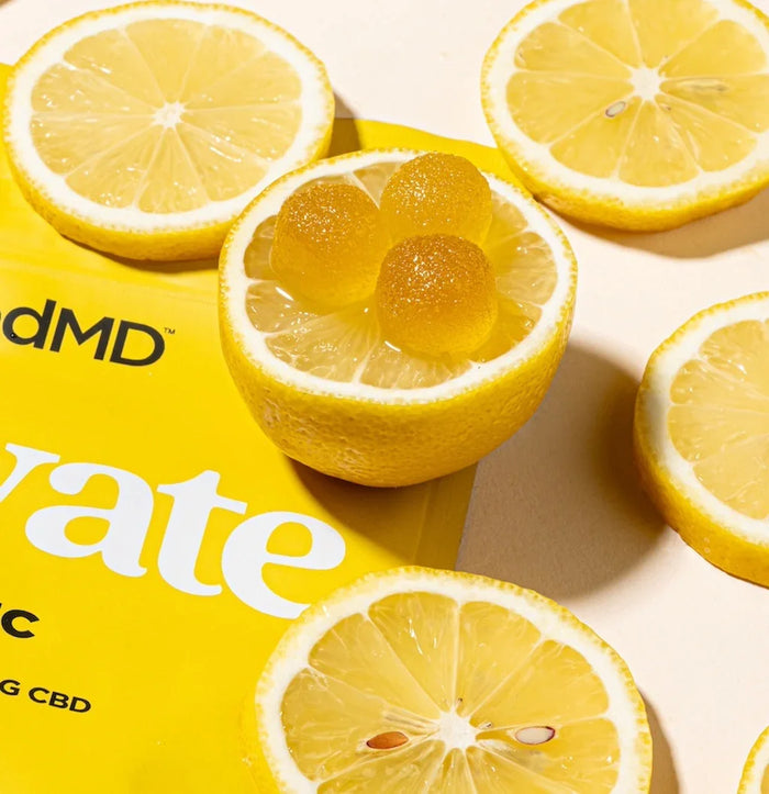 Lemon slices and yellow gummies arranged on a yellow package, suggesting citrus CBD edibles.