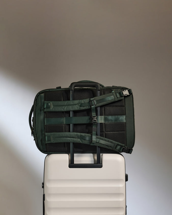 a green and black bag on top of a white suitcase
