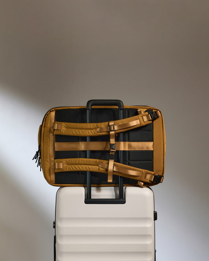 a brown and black bag on top of a white suitcase