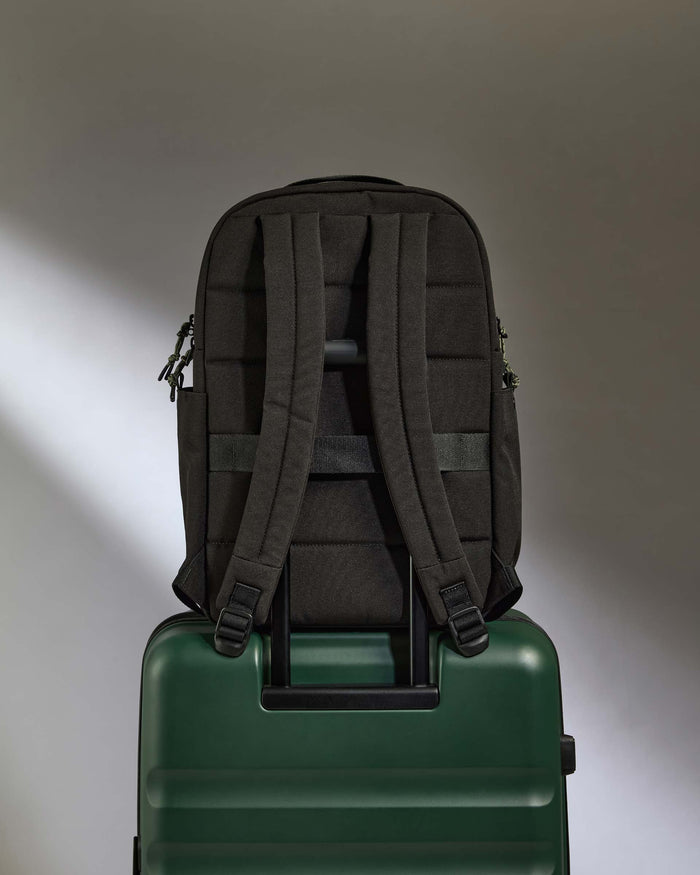 a backpack on top of a green suitcase
