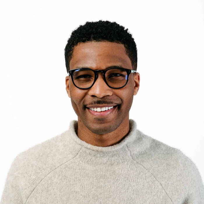 Man wearing glasses and a light gray sweater on a white background