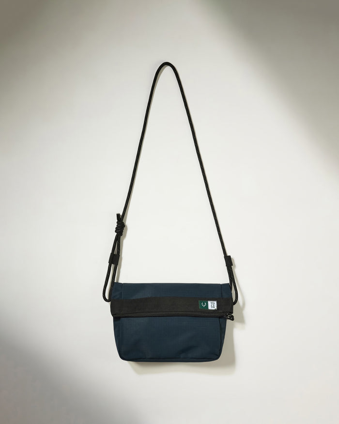 a blue bag with a black strap on a white wall