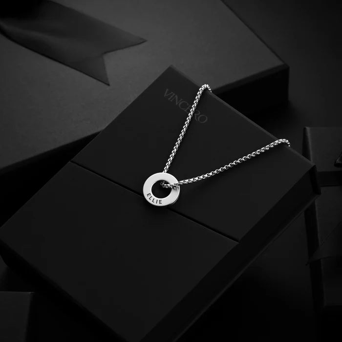 Silver necklace with a circular pendant on a black box with 'VINCERO' branding.