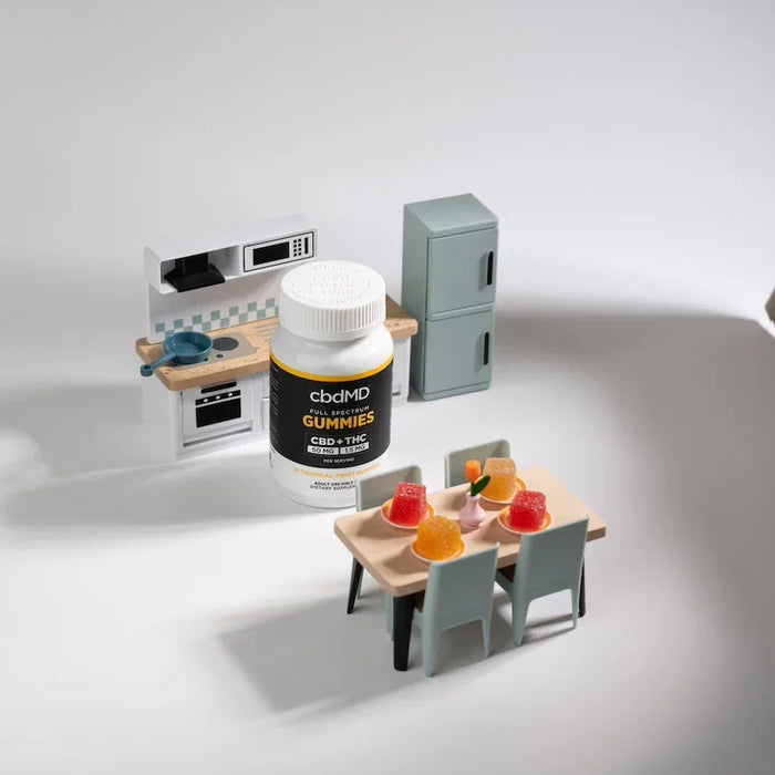 CBD gummies bottle with assorted gummies on a small table in a miniature kitchen setting; Strength: 1500MG;