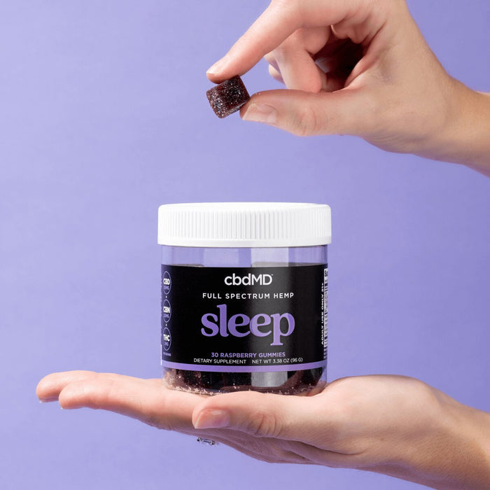 Hand holding a jar of full spectrum hemp sleep gummies with one gummy being picked up