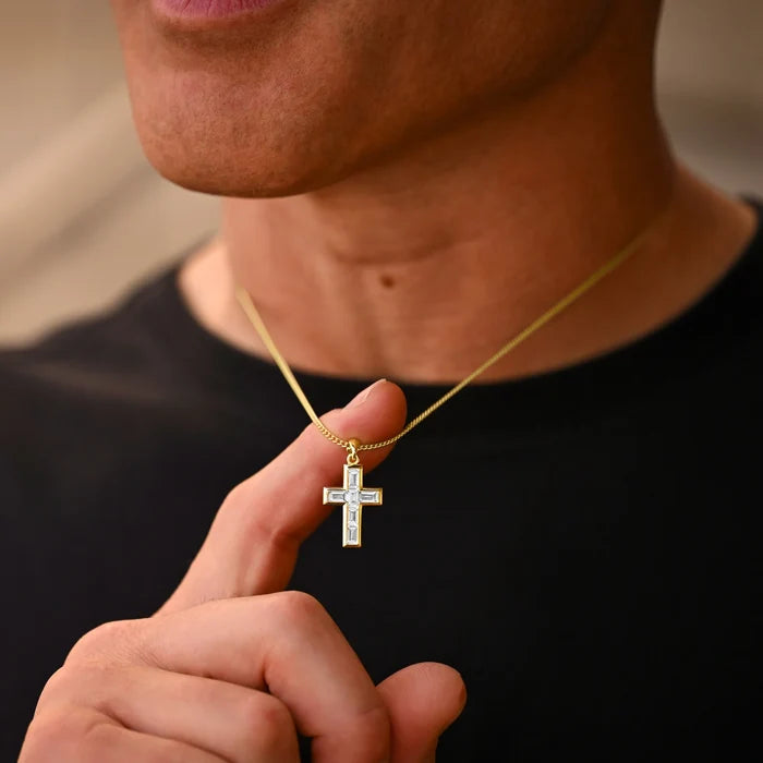 Person holding a gold necklace with a cross pendant