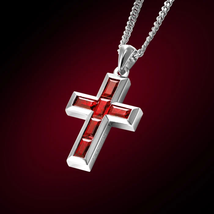 Silver cross pendant with red stones on a dark red background