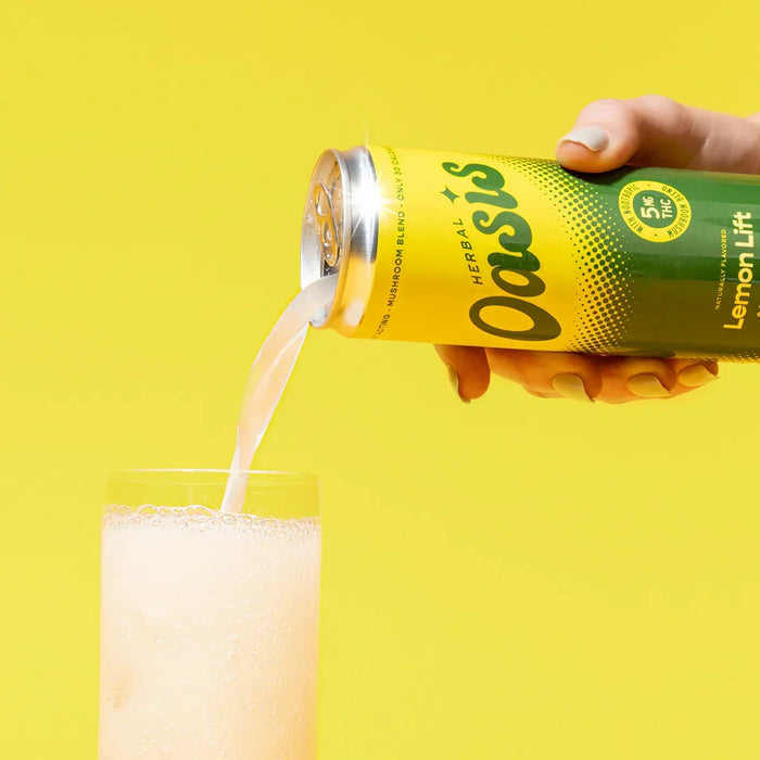 Hand pouring Lemon Lift herbal sparkling drink from a can into a glass on yellow background; Flavor: Lemon Lift;