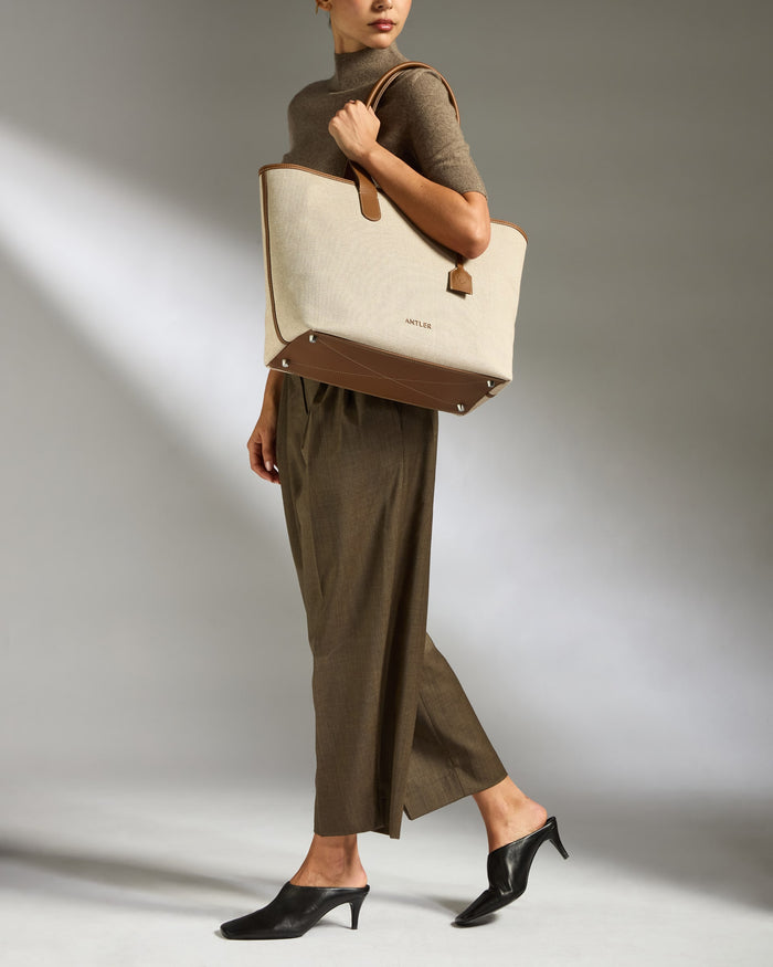 a woman in a brown dress holding a large bag