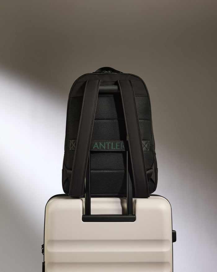 a black backpack on top of a white suitcase