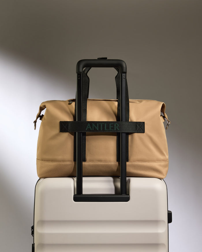 a tan bag on top of a white suitcase