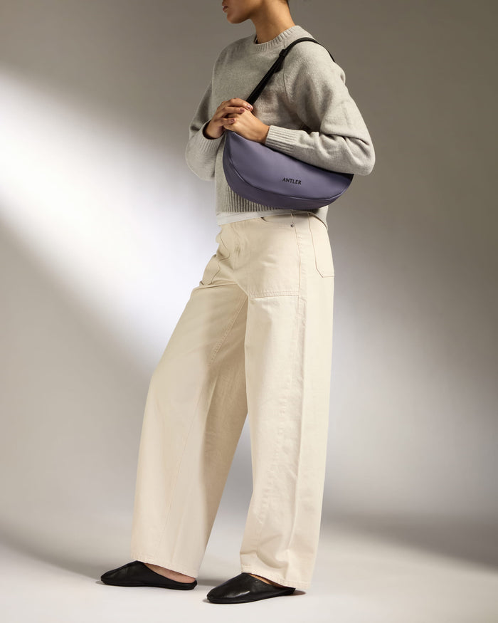 a woman wearing a grey sweater and white pants