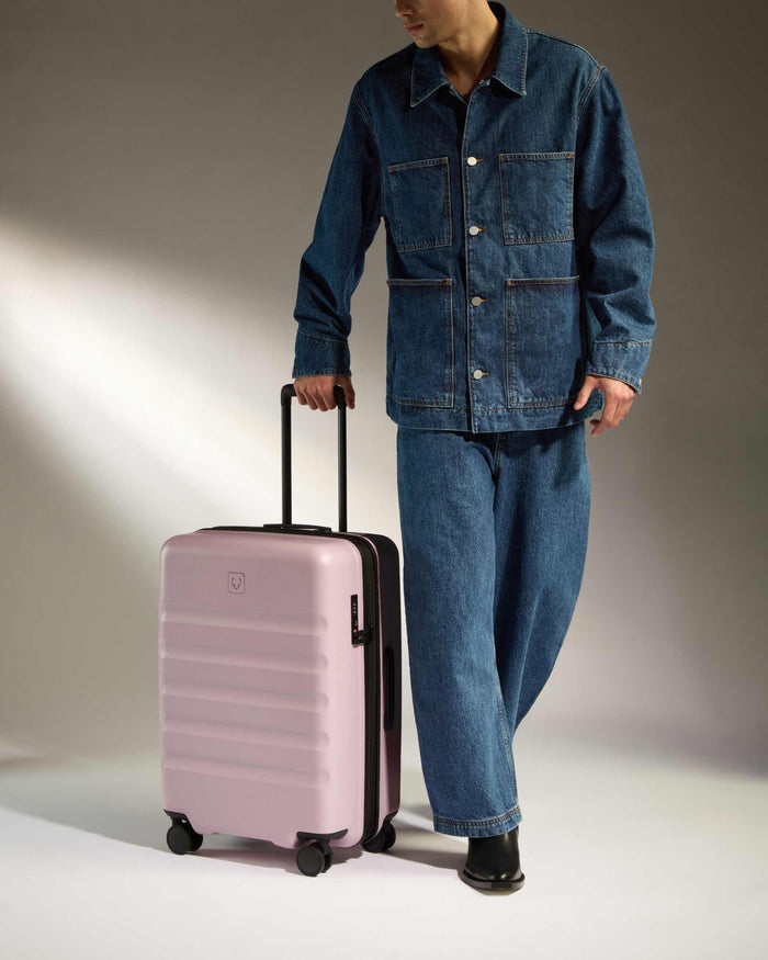 a man in a denim suit and jeans with a pink suitcase