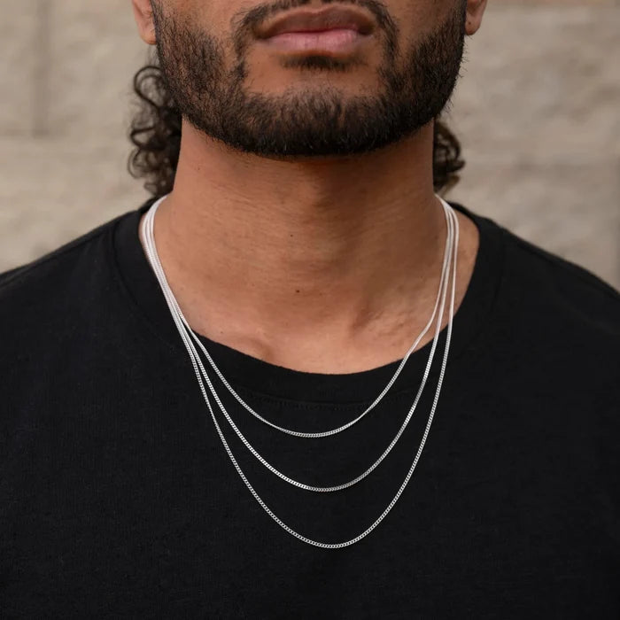 Man wearing a silver chain necklace against a neutral background