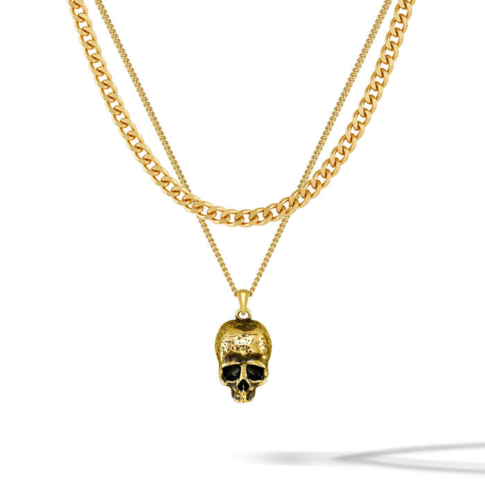 Gold chain necklace with a skull pendant on a white background